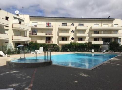 un grand bâtiment avec une piscine en face d'un bâtiment dans l'établissement Studio + piscine+ parking privé. Quartier Minimes, à La Rochelle