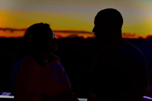 a man and a woman standing in front of a sunset at Mangabeiras - Casa de Hóspedes in Alto Paraíso de Goiás