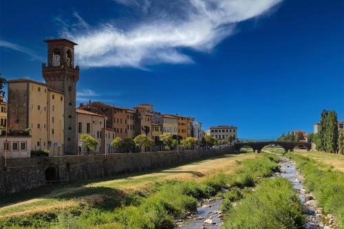 a river in front of a city with a clock tower at Mansarda Pescia in Pescia