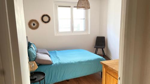 une chambre avec un lit bleu et une fenêtre dans l'établissement Michel Perrot, à Concarneau