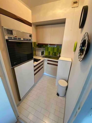 Il comprend une cuisine avec des appareils électroménagers blancs et du carrelage. dans l'établissement Charmant studio en bord de mer, à La Baule