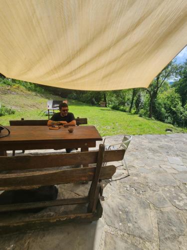 a man sitting at a picnic table under a tent at Contea del Piano in Piteglio