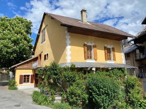 une maison jaune avec un toit en gambrel dans l'établissement Le Pied de Ville Morgon, à Embrun