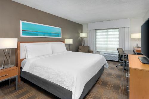 マイアミにあるHoliday Inn Miami-Doral Area, an IHG Hotelの大きなベッドとデスクが備わるホテルルームです。