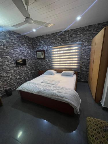 a bedroom with a bed and a brick wall at Calawazobia Hotel in Uyo