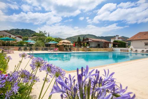 a pool at a resort with purple flowers at Hotel Restaurant Bonnet in Saint-Pée-sur-Nivelle
