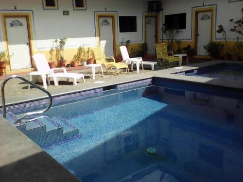 a swimming pool with chairs and a table at Hotel Sarabi in Barra de Navidad