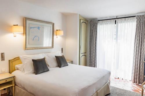 a bedroom with a large white bed and a window at Du Côté Des Olivades in Paradou