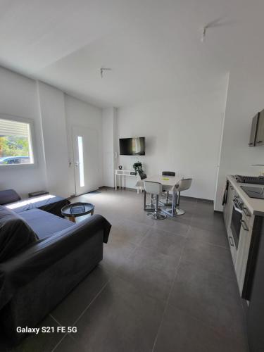 un salon avec un canapé noir et une cuisine dans l'établissement T2 bord de mer, à Albitreccia