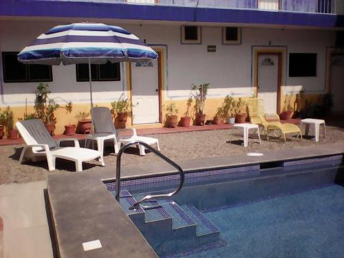 a pool with chairs and an umbrella next to it at Hotel Sarabi in Barra de Navidad