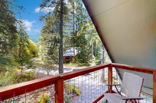 a balcony with two chairs and a view of a forest at Woodland Wanderlust in Glacier
