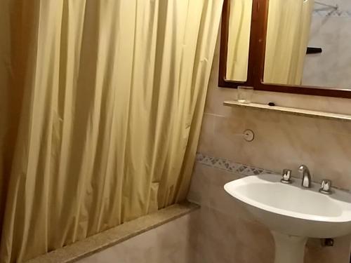 een badkamer met een wastafel en een douchegordijn bij Apart Los Menhires in Termas de Río Hondo