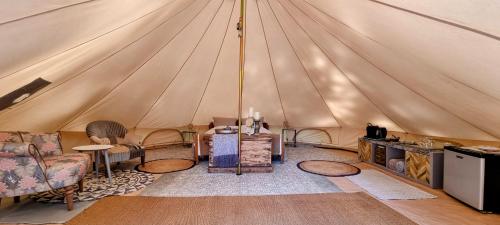 une tente avec un canapé et des chaises dans une chambre dans l'établissement Luxury Bell Tent at Camping La Fortinerie, à Mouliherne