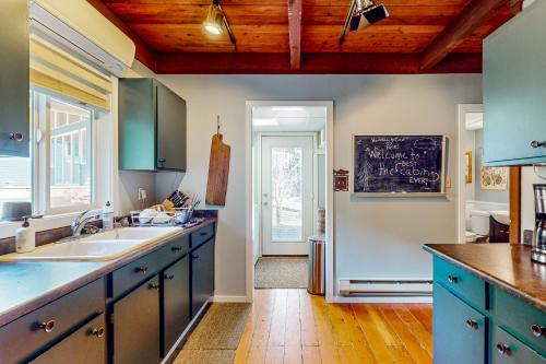 a kitchen with blue cabinets and a chalkboard on the wall at Woodland Wanderlust in Glacier