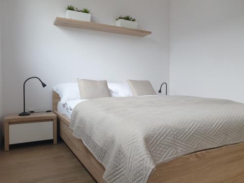 una camera bianca con un grande letto e due piante di Near the airport- Apartments a Cracovia