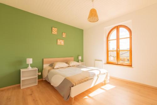 Dormitorio verde con cama y ventana en Gîte de la Louvière - maison de campagne, en Grandpré