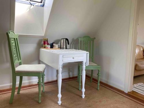 a white table and two green chairs in a room at Smukke omgivelser i Troense in Svendborg