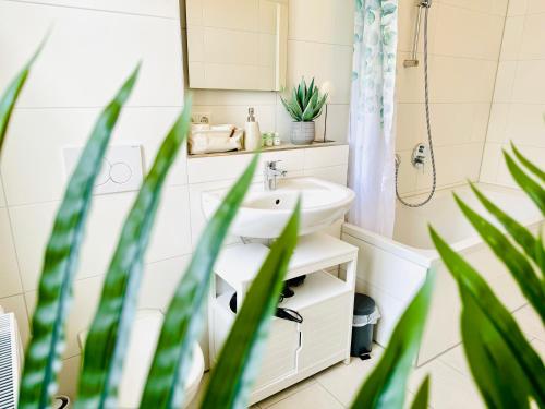 a bathroom with a sink and a mirror and plants at E&K living - design Apartments - SKY-TV - Audi - IN village - free parking in Ingolstadt