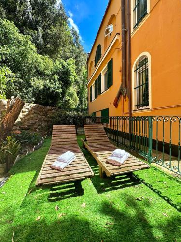 two wooden benches sitting in the grass next to a building at Casa • Paraggi • in Paraggi