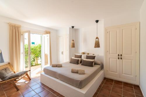 a white bedroom with a large bed and a chair at Cal Xoc - Apartamento paradisíaco junto al mar in Son Xoriguer