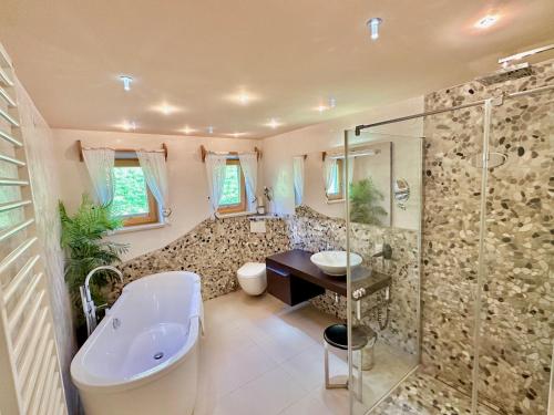 een badkamer met een bad, een wastafel en een douche bij Aparthotel Krösbacher in Fulpmes