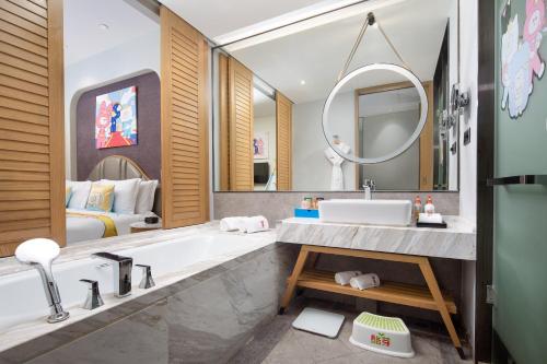 Un baño con bañera, lavabo y espejo. en Crowne Plaza QingdaoOriental Movie Metropolis by IHG, en Huangdao