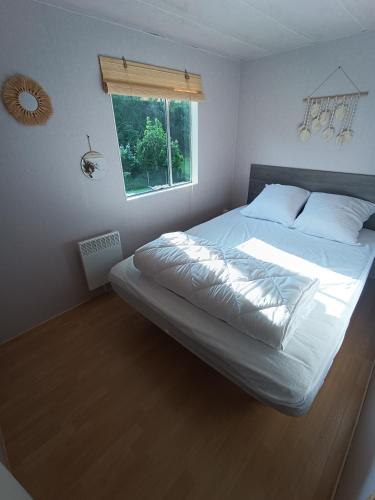 un grand lit dans une chambre avec une fenêtre dans l'établissement Camping les goélands, à Saint-Martin-Plage