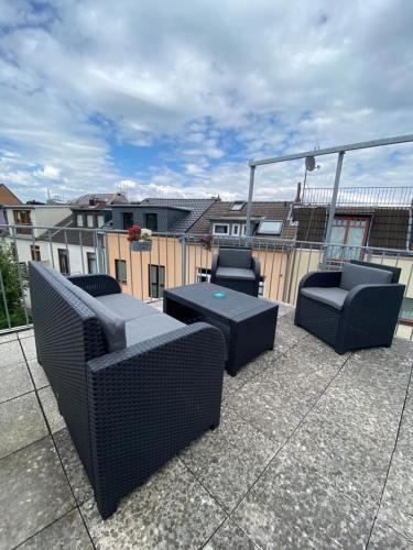 3 Stühle und ein Tisch auf einer Terrasse mit Gebäuden in der Unterkunft Walle Retreat Zentral&Gemütlich in Bremen