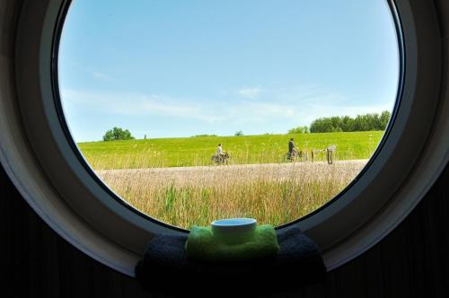 a round window looking out at people riding bikes in a field at BestMarine Waterchalets Flevo Marina in Lelystad