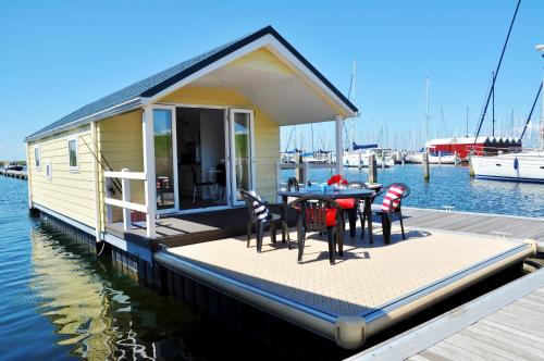 una casa en un muelle con mesa y sillas en BestMarine Waterchalets Flevo Marina, en Lelystad