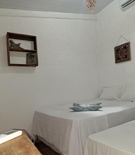 a white bedroom with two beds and a mirror at Estresse Zero in Atins