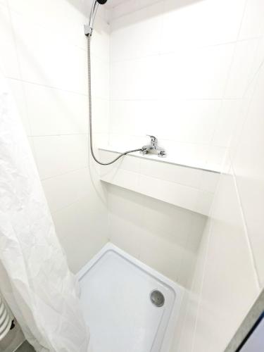 ein weißes Bad mit einer Dusche und einem Waschbecken in der Unterkunft Poczekalnia Turystyczna in Ratibor
