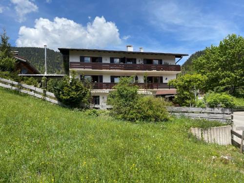 une maison sur le côté d'une colline herbeuse dans l'établissement Ferienwohnung Tiefenbach mit Garten, à Oberstdorf