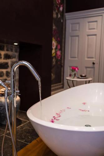 a bathroom with a white tub with water coming out at Easby Hall in Richmond