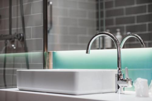 a bathroom sink with two faucets and a mirror at Holiday Inn Express Ajaccio by IHG in Ajaccio