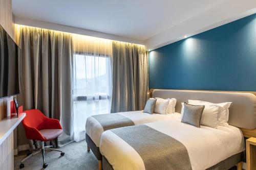 a hotel room with two beds and a red chair at Holiday Inn Express Ajaccio by IHG in Ajaccio