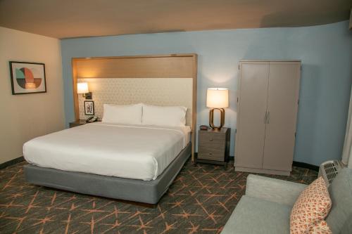 Holiday Inn New Orleans West Bank Tower, an IHG Hotel في غريتنا: غرفة نوم بسرير كبير وباب للخزانة
