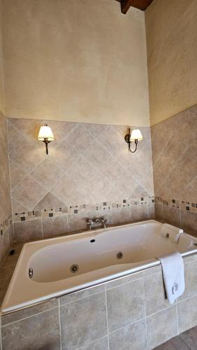 a bath tub in a bathroom with two lights on the wall at La Reina Hotel in Santa Rosa de Calamuchita