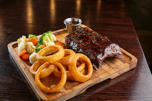 a plate of ribs and onion rings on a table at Holiday Inn New Orleans West Bank Tower by IHG in Gretna
