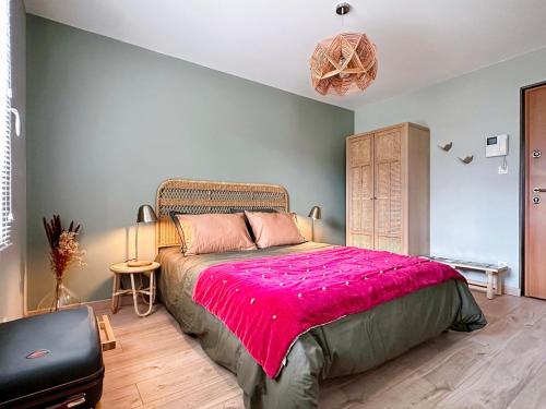 a bedroom with a large bed with a pink blanket at Charmant studio avec parking in Eguisheim