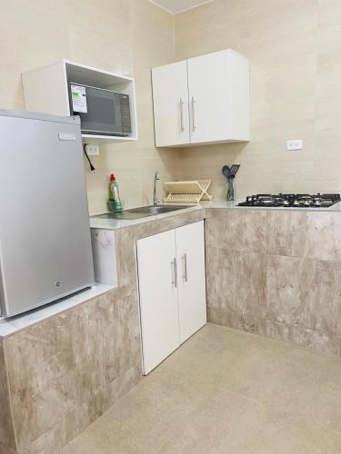 a kitchen with white cabinets and a sink and a stove at Casa Gaviota Dorada in Baños