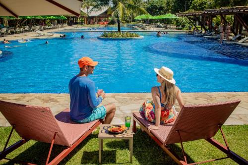 a man and woman sitting in chairs by a pool at Vivá Porto de Galinhas Resort in Porto De Galinhas