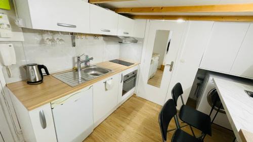 une petite cuisine avec des armoires blanches et un évier dans l'établissement Studio 2 pers - Cœur de Paris, à Paris