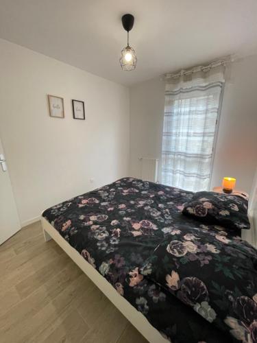 une chambre avec un lit avec un couvre-lit fleuri dans l'établissement Appartement cosy proche Paris, à Bezons