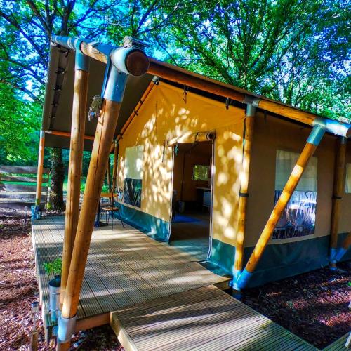 une maison avec une terrasse couverte et une terrasse en bois dans l'établissement Luxury Safari Tent with Hot Tub at Camping La Fortinerie, à Mouliherne