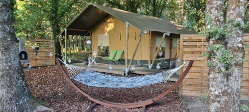 eine Hängematte vor einer Hütte im Wald in der Unterkunft Luxury Safari Tent with Hot Tub at Camping La Fortinerie in Mouliherne