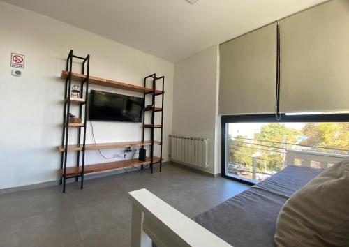 1 dormitorio con 1 cama y TV en la pared en Pionero en Neuquén