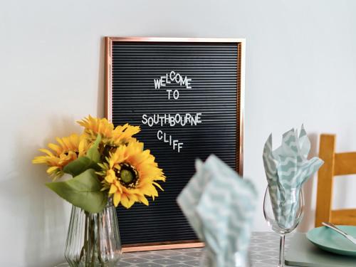 a table with a vase of sunflowers in front of a sign at Mary Bowes Terrace in Bournemouth