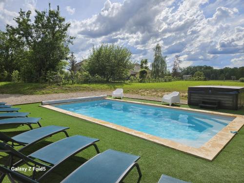 een groot zwembad met stoelen en een grill bij Au gîte Sérénité in Mouthier-en-Bresse