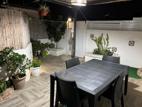 une table et des chaises dans une terrasse avec des plantes en pot dans l'établissement Holiday Rooms Ninfa, à Avola